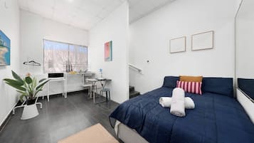 A modern bedroom with a bed, a desk, and a window.