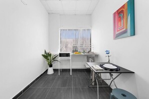 A small, modern kitchen with a window, a microwave, a sink, and a dining table.