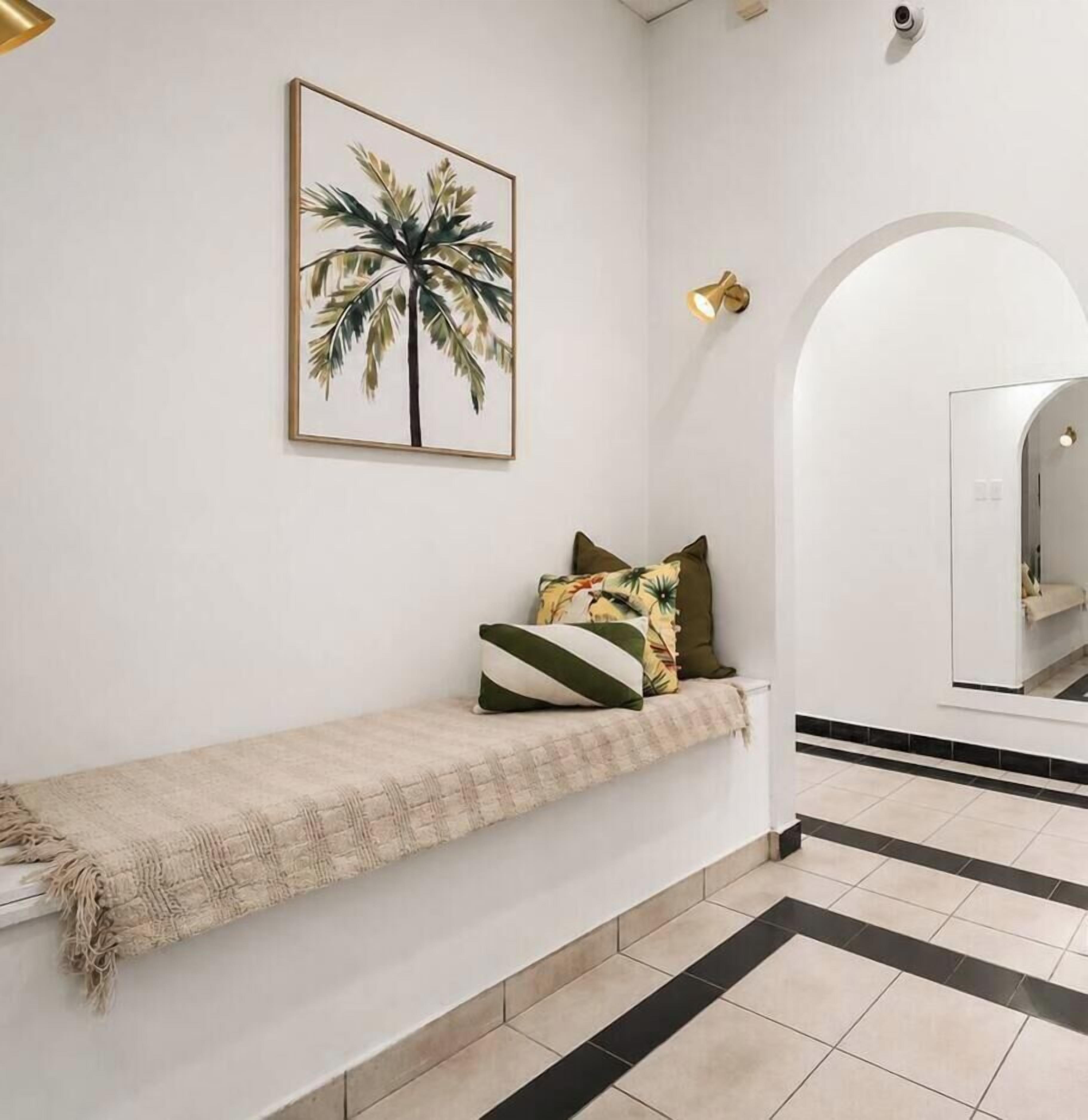 A hallway with a bench, a potted plant, and a mirror.
