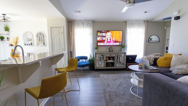 Un soggiorno moderno con televisore, divano e angolo bar.