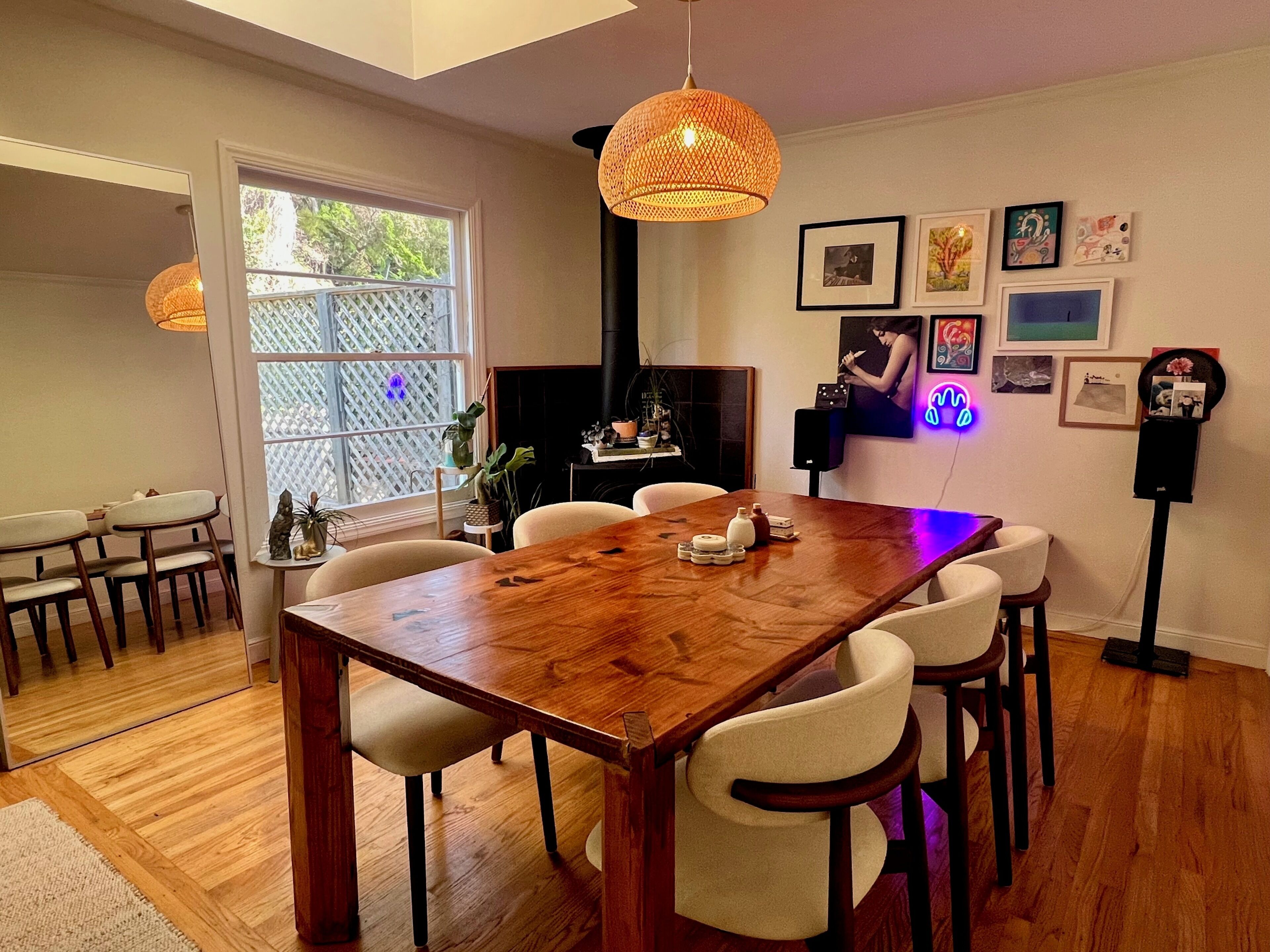 A dining area with a wooden table and chairs, a hanging light fixture, and a fireplace.