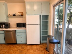 A compact kitchen with a refrigerator, microwave, coffee maker, and dishwasher.