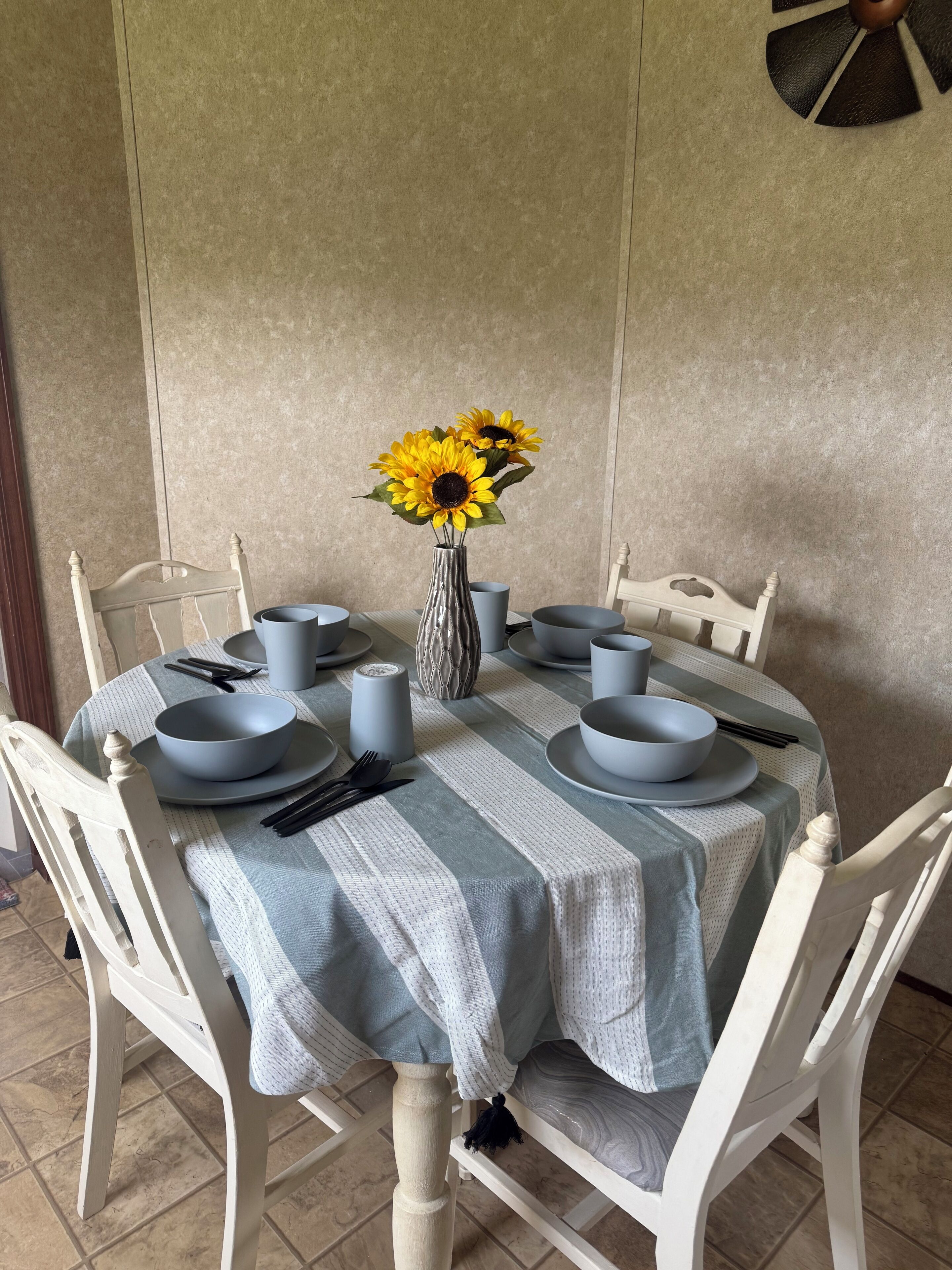 A dining table set with plates, bowls, and a vase with flowers.