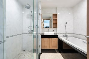 Un baño moderno con cabina de ducha de vidrio, una bañera independiente y un tocador con lavabo.