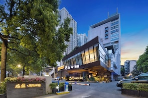 A hotel entrance with a modern design, a visible signboard, and a gated driveway.