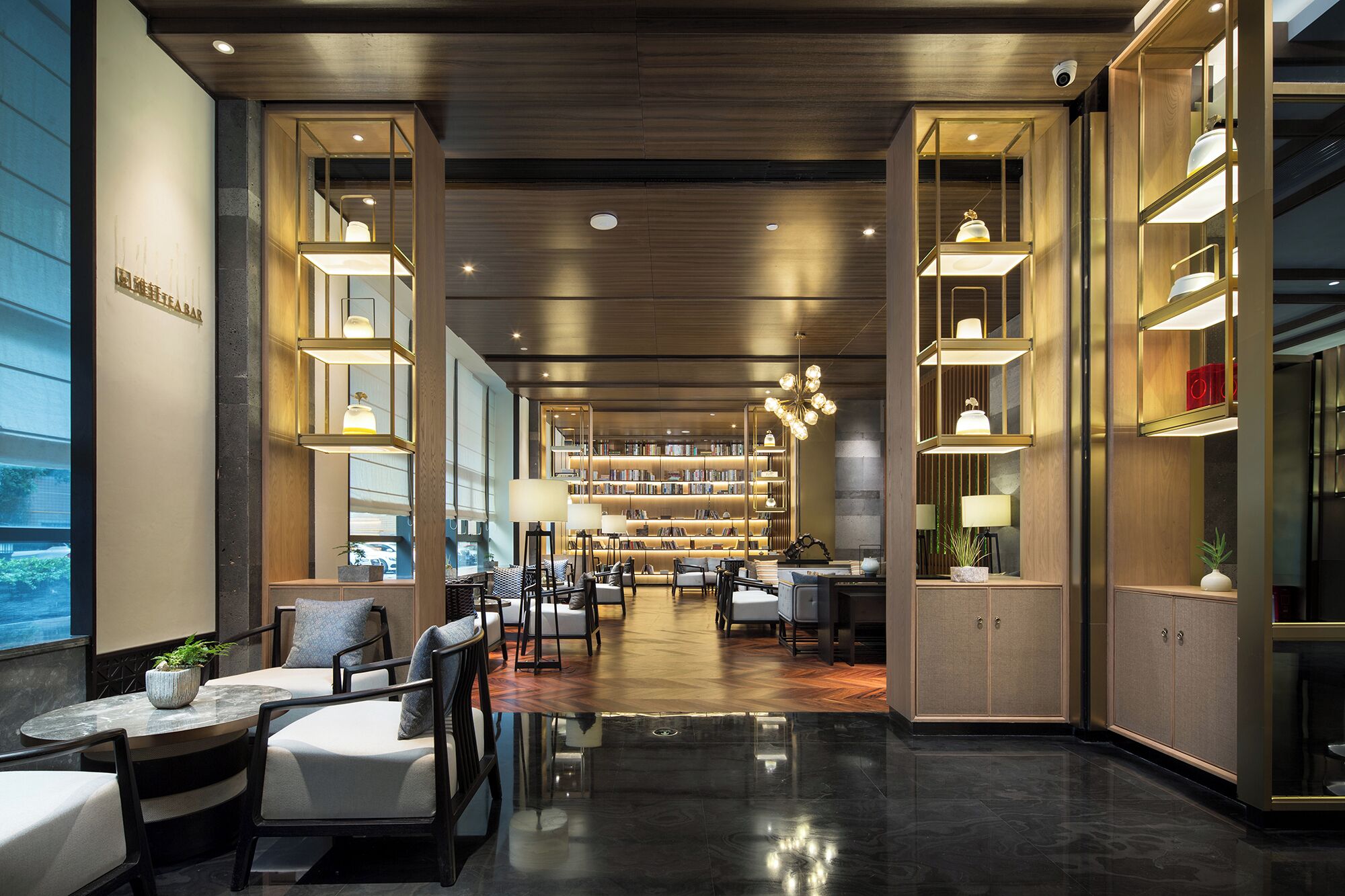 A modern library with bookshelves, seating areas, and a bar.