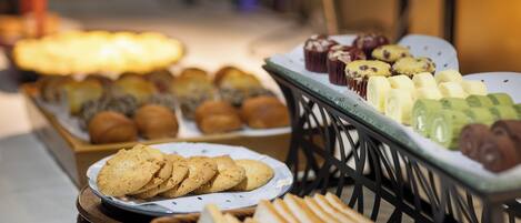 A variety of baked goods displayed on a table, including cookies, muffins, and bread.