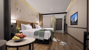 Une chambre d’hôtel moderne avec un grand lit, une table à manger avec des fruits, une télévision et une vue sur la ville.