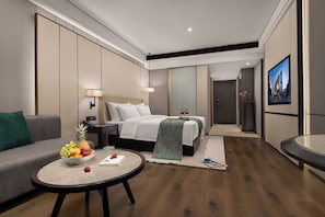 Habitación de hotel moderna con cama, sofá, mesa de comedor y vistas a la ciudad.