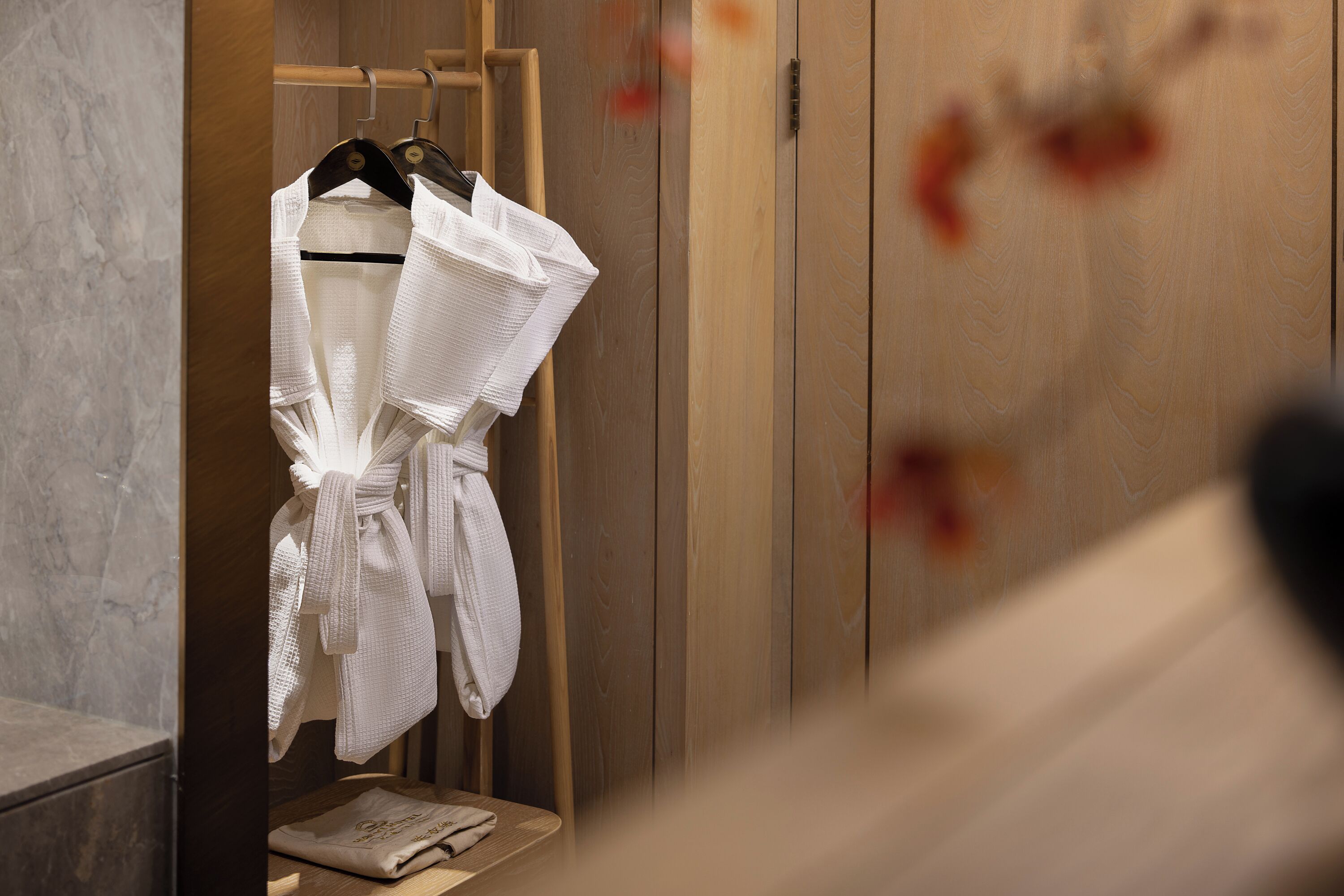 Guarda-roupa de madeira com espelho, uma cadeira de madeira e um porta-toalhas com toalhas brancas.