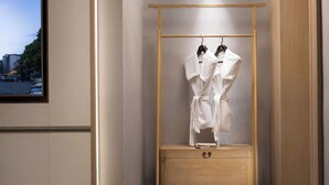 Un dressing avec une armoire en bois, une tringle à vêtements et une petite commode en bois.