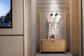 A walk-in closet with a wooden wardrobe, a hanging rack, and a small wooden chest.