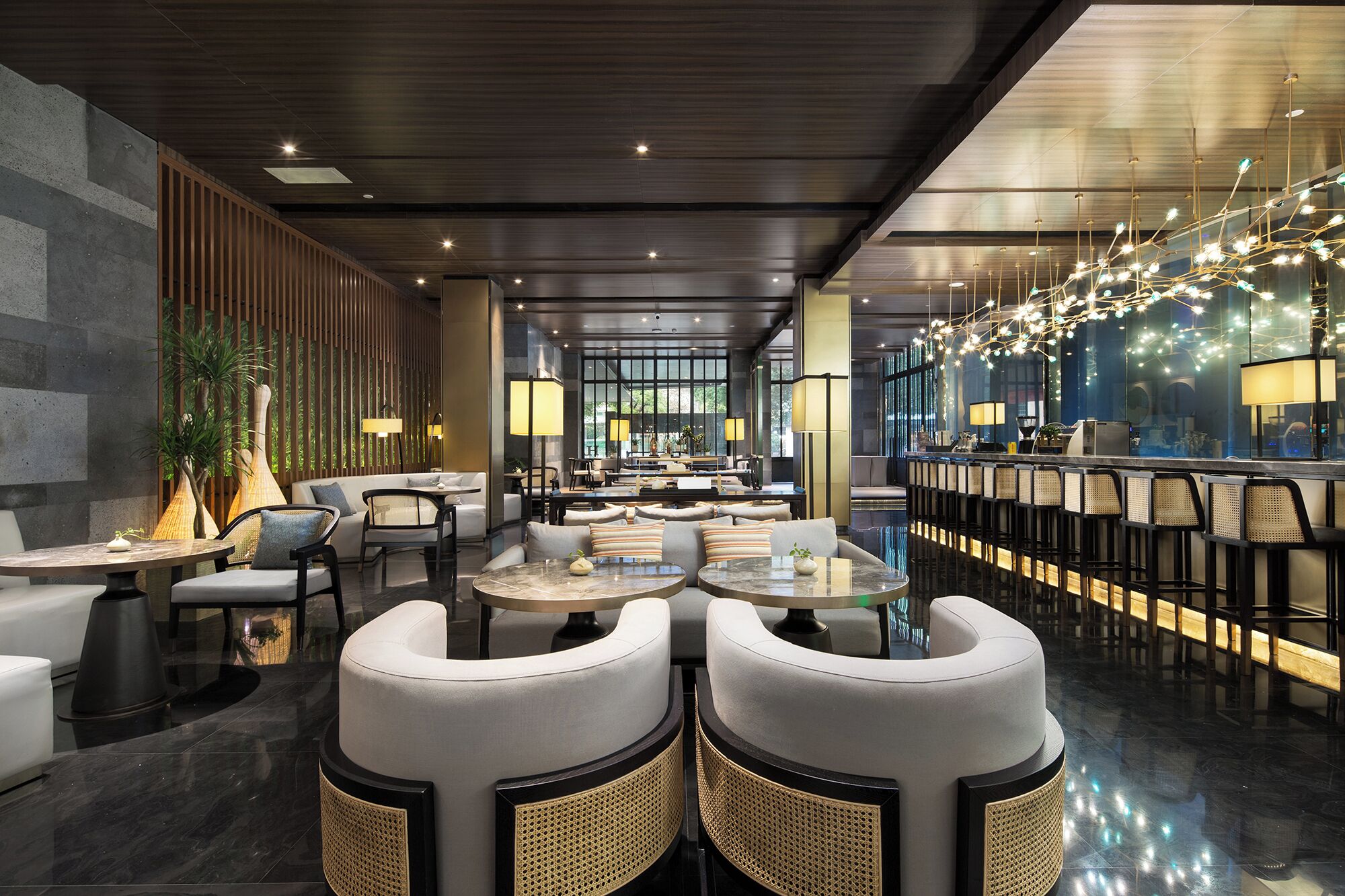 Un hall d’hôtel moderne, doté d’espaces de détente, d’un bar et d’un comptoir d’accueil.