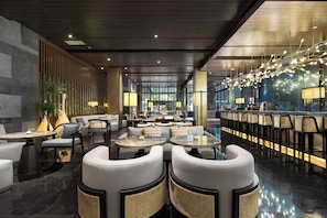 A modern hotel lobby with seating areas, a bar, and a reception desk.