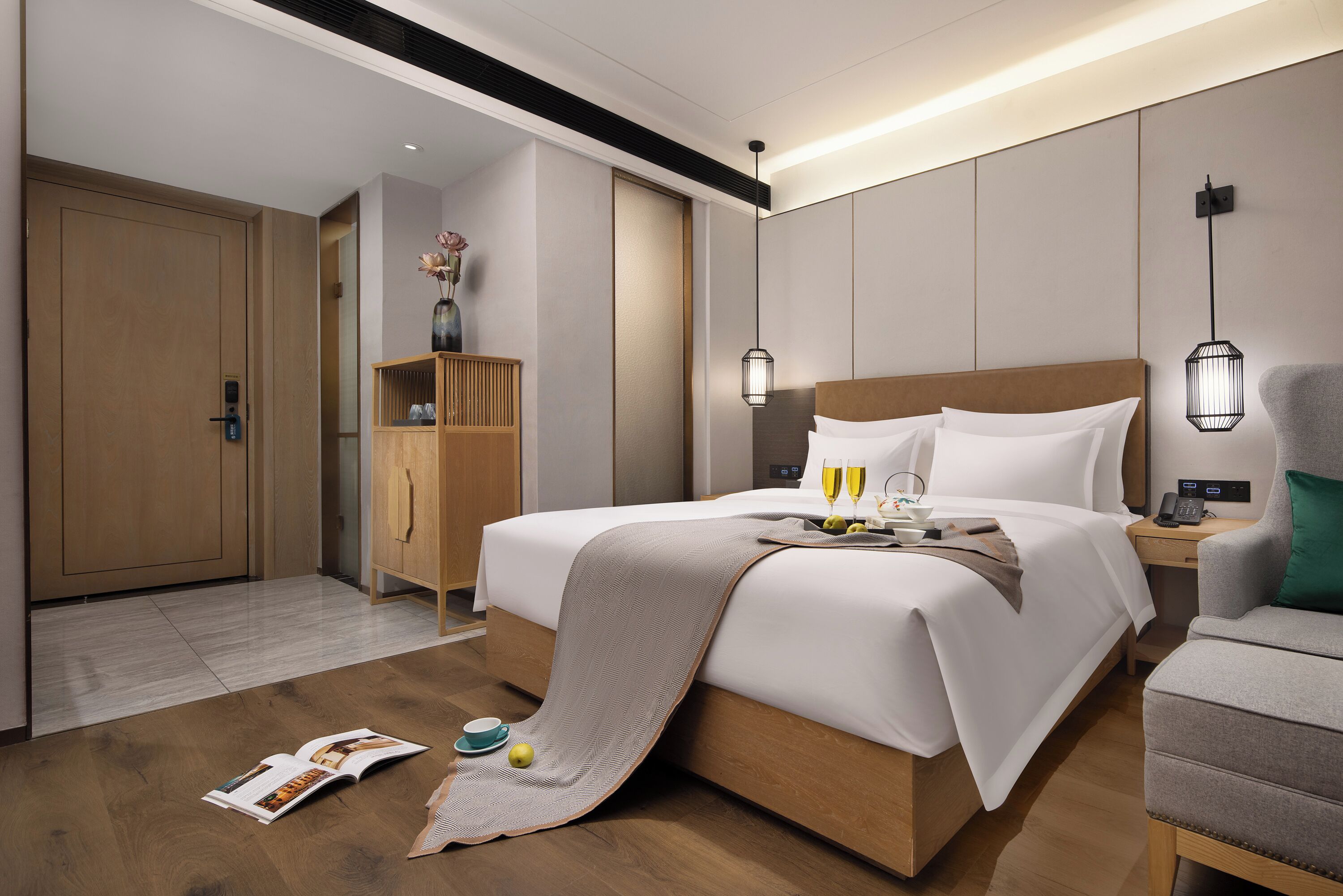 Habitación de hotel moderna con una cama grande, mesitas de noche, un armario y una pequeña zona de estar.