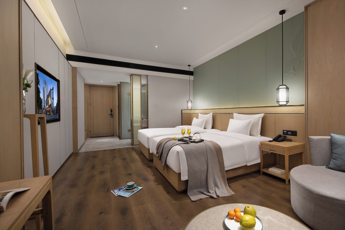 Una habitación de hotel moderna con una cama grande, mesitas de noche, una zona de estar y un televisor.