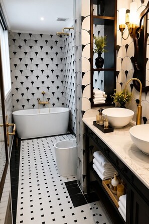 Un baño moderno con una bañera independiente, un tocador con un espejo grande y un suelo con diseño.