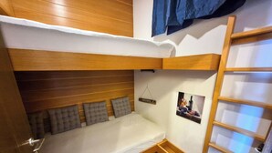 Una camera con letto a castello, una testiera in legno, un piccolo comodino e una mensola a parete.