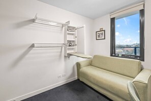Ein Zimmer mit einer Couch, einem Heizkörper, einem Fenster mit Blick und einem gerahmten Bild an der Wand.