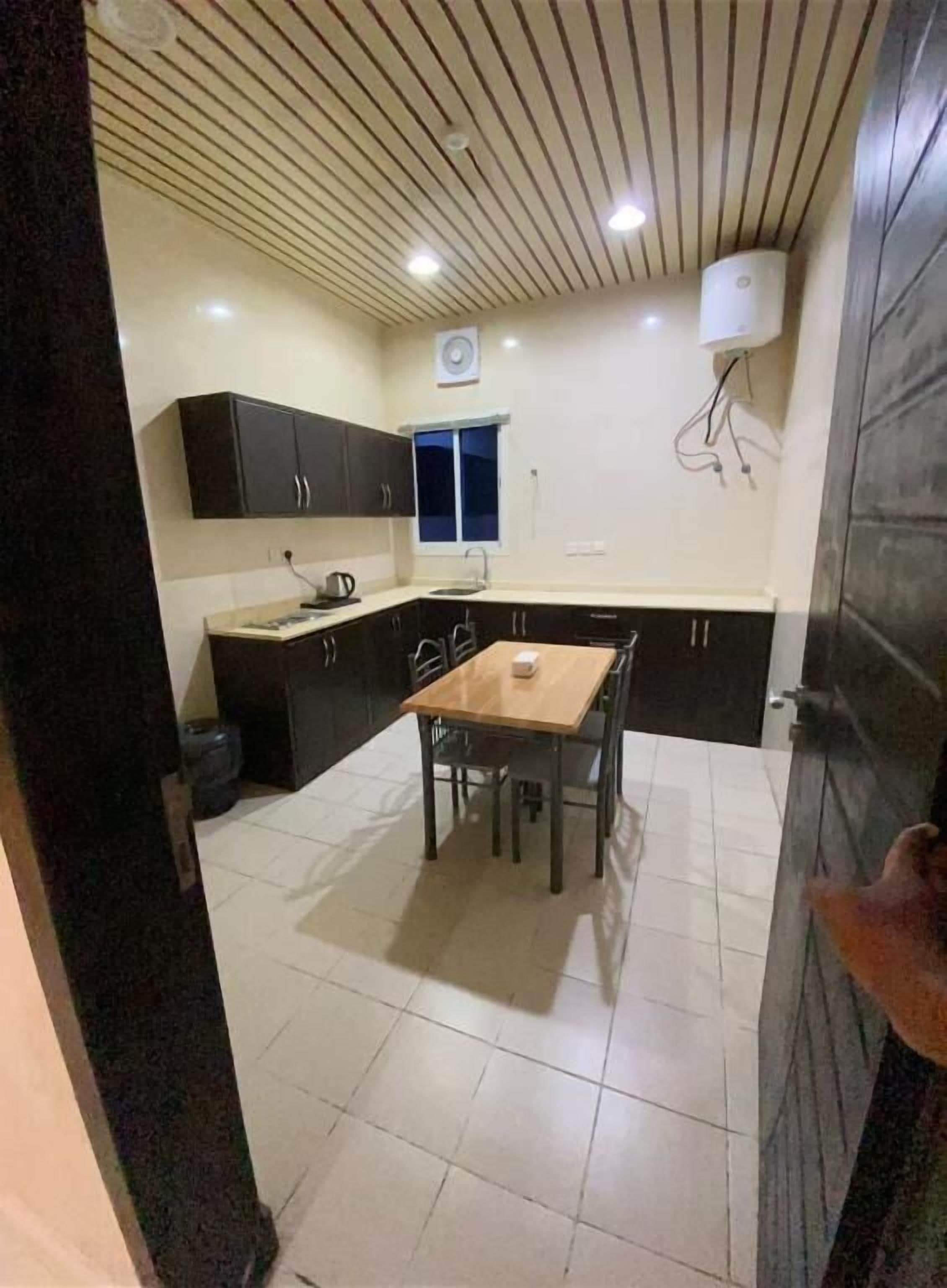 A compact kitchen with a dining table, cabinets, and a ceiling fan.
