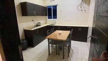 A compact kitchen with a dining table, cabinets, and a ceiling fan.