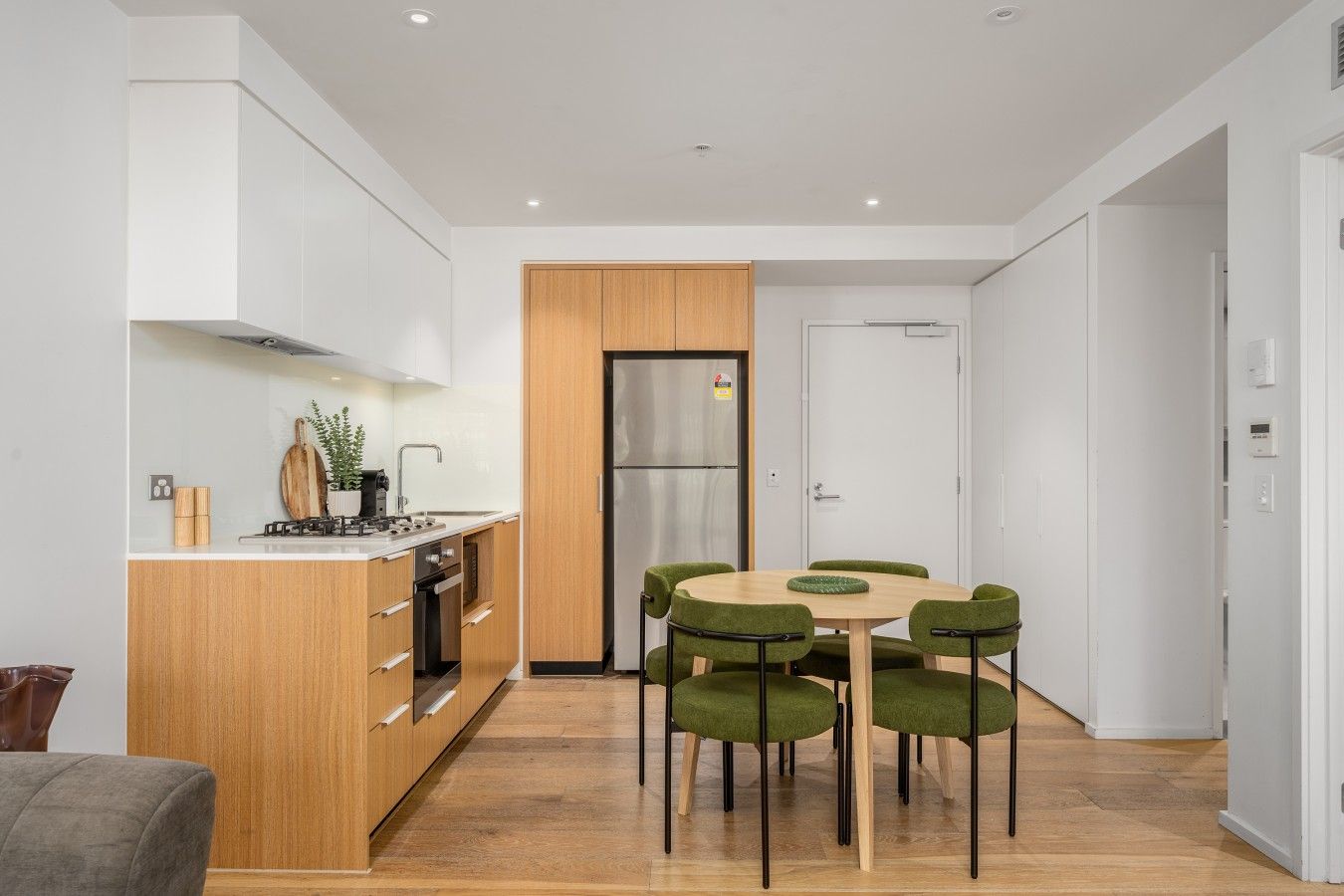 A modern kitchen with a central island, wooden cabinets, and a built-in oven.