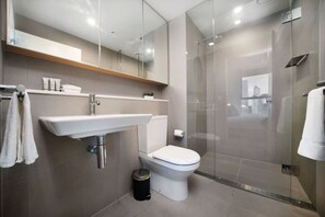 Ein modernes Badezimmer mit einer gläsernen Dusche, einem weißen Waschbecken und einer Toilette.