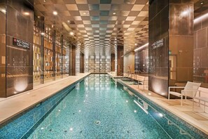 Ein Hallenbad mit kariertem Deckenmuster, Glaswänden und Schildern, die darauf hinweisen, dass das Tauchen über einer Tiefe von 1,2 Metern nicht erlaubt ist.