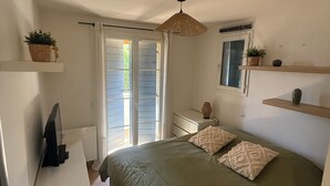 Ein Schlafzimmer mit einem Bett, einem Schminktisch, einem Fernseher, einem Deckenventilator und einem Fenster mit Vorhängen.