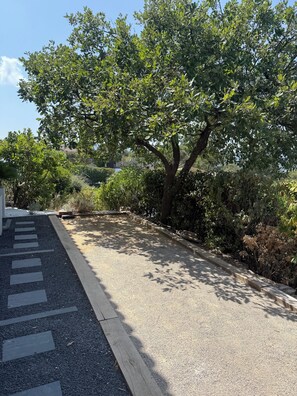 Ein gepflasterter Weg mit Bordstein, umgeben von dichter Vegetation und Bäumen.