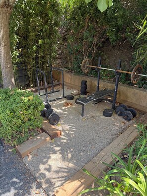A weightlifting area with a bench press, barbell, and weight plates. - House with a View of the Castle • Jacuzzi • Fire pit • Fitness Area • Beaches 10 minutes away (Cogolin)