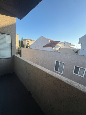 Un balcó amb vista a edificis veïnals, una antena parabòlica i una finestra amb persianes.