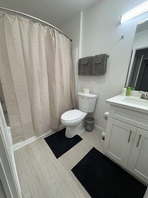 Ein Badezimmer mit Toilette, Duschvorhang, Waschbecken und Spiegel.