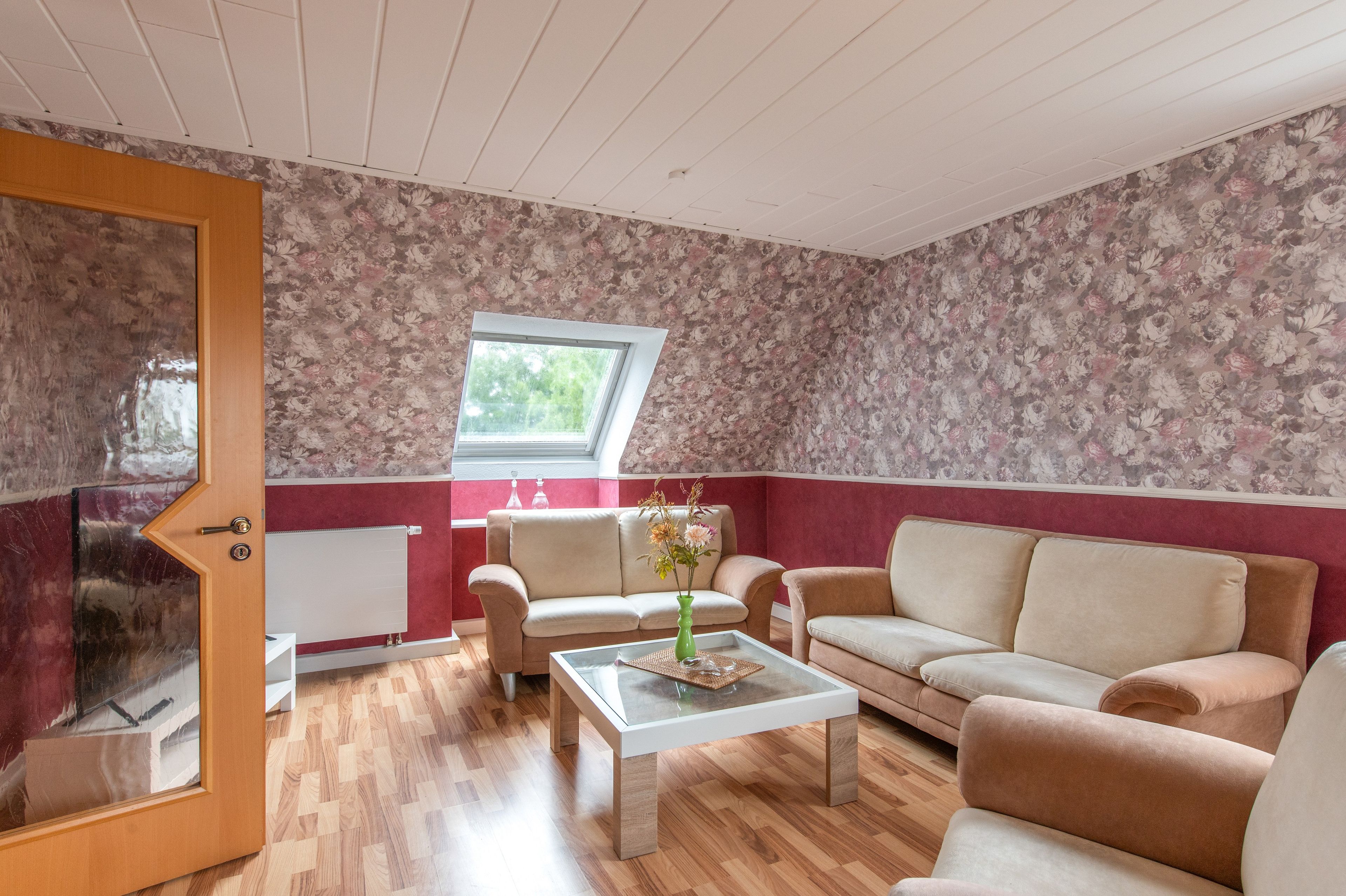 Sala de estar com piso de madeira, dois sofás, uma mesa de centro e janela com vista para área verde.