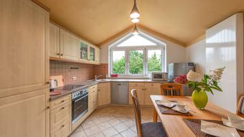 A kitchen with wooden cabinets, a dishwasher, a stove, and a dining area with a table and chairs.