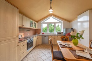 A kitchen with wooden cabinets, a dishwasher, a stove, and a dining area with a table and chairs.