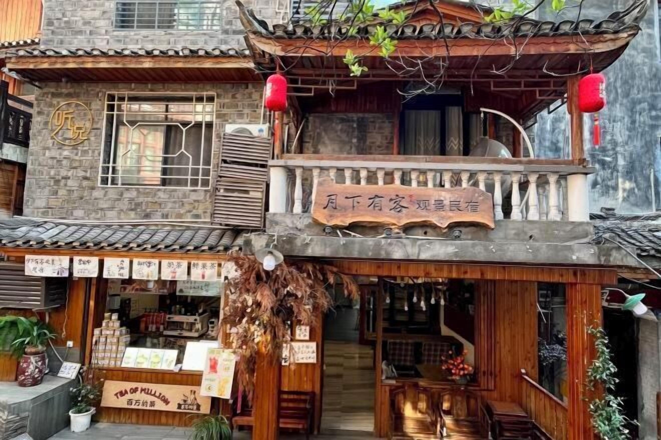 Un edificio tradicional con una tienda de té en la planta baja, un balcón con un letrero y una escalera de madera que lleva al piso superior.
