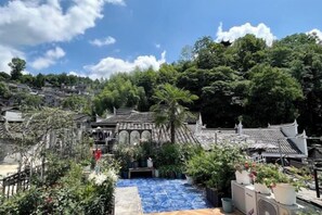 A traditional courtyard with a blue tiled pool, surrounded by potted plants and traditional architecture. - Phoenix Moonlight View Inn (Fenghuang County)