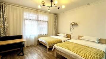 A room with two beds, a desk, and a chandelier.