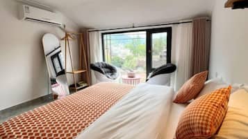 Habitación de hotel con una cama grande, una silla, una mesita y una ventana con vistas.