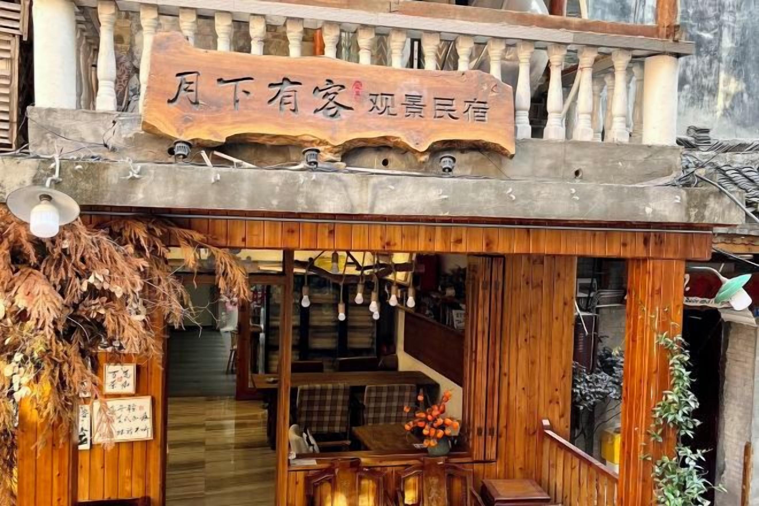 Ein traditionelles Holzhaus mit einem Schild, einer Treppe und einem sichtbaren Sitzbereich im Inneren.