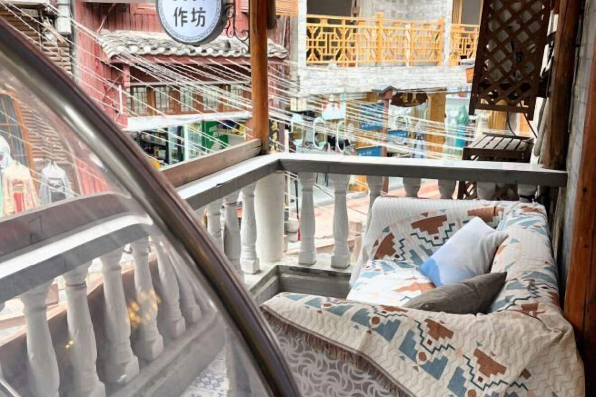 Un balcón con un sofá estampado y vistas a una calle con andamios.