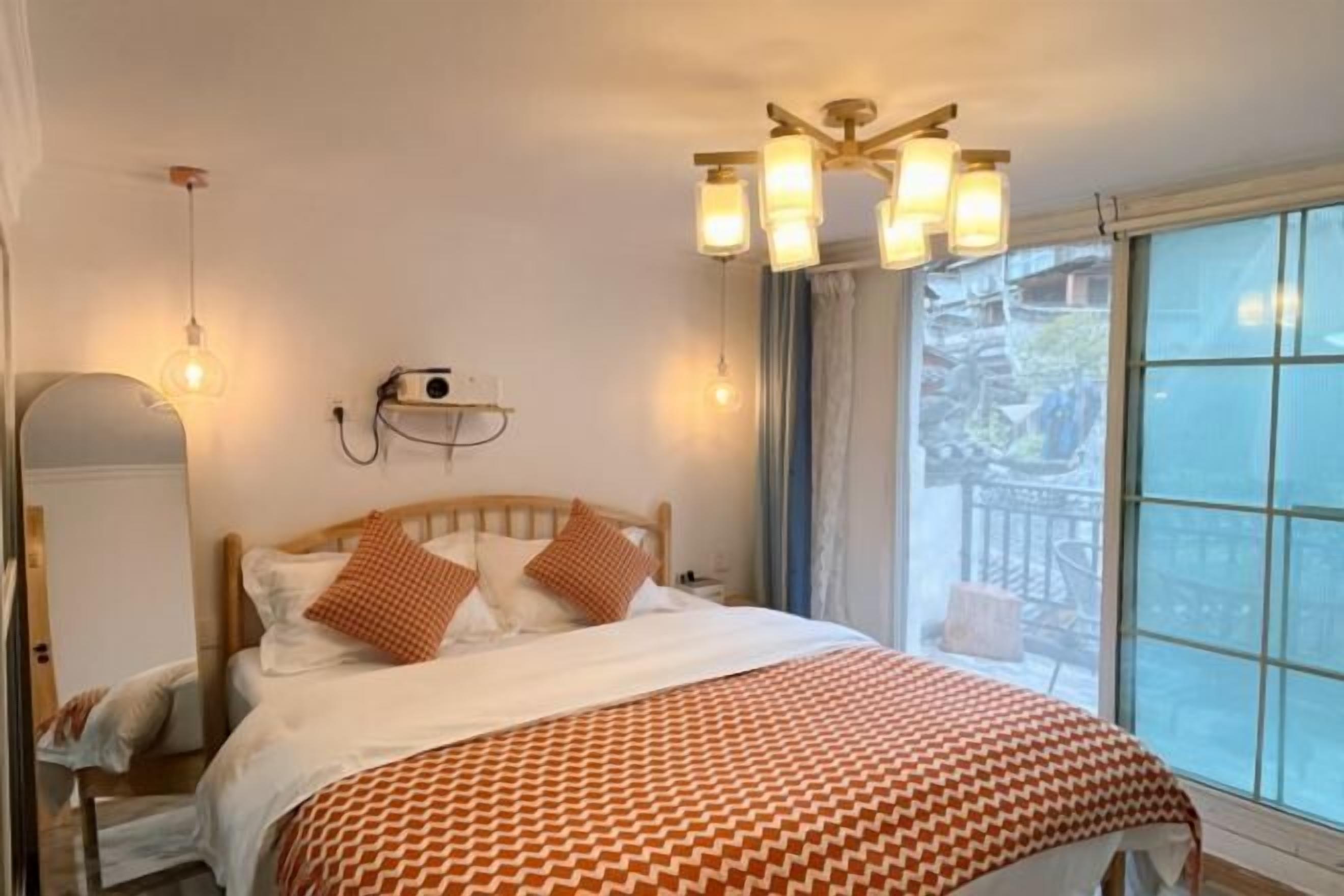 A hotel room with a bed, bedside table, lamp, and a window with a view.