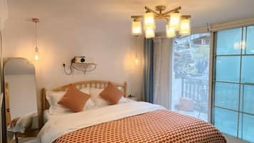 A hotel room with a bed, bedside table, lamp, and a window with a view.