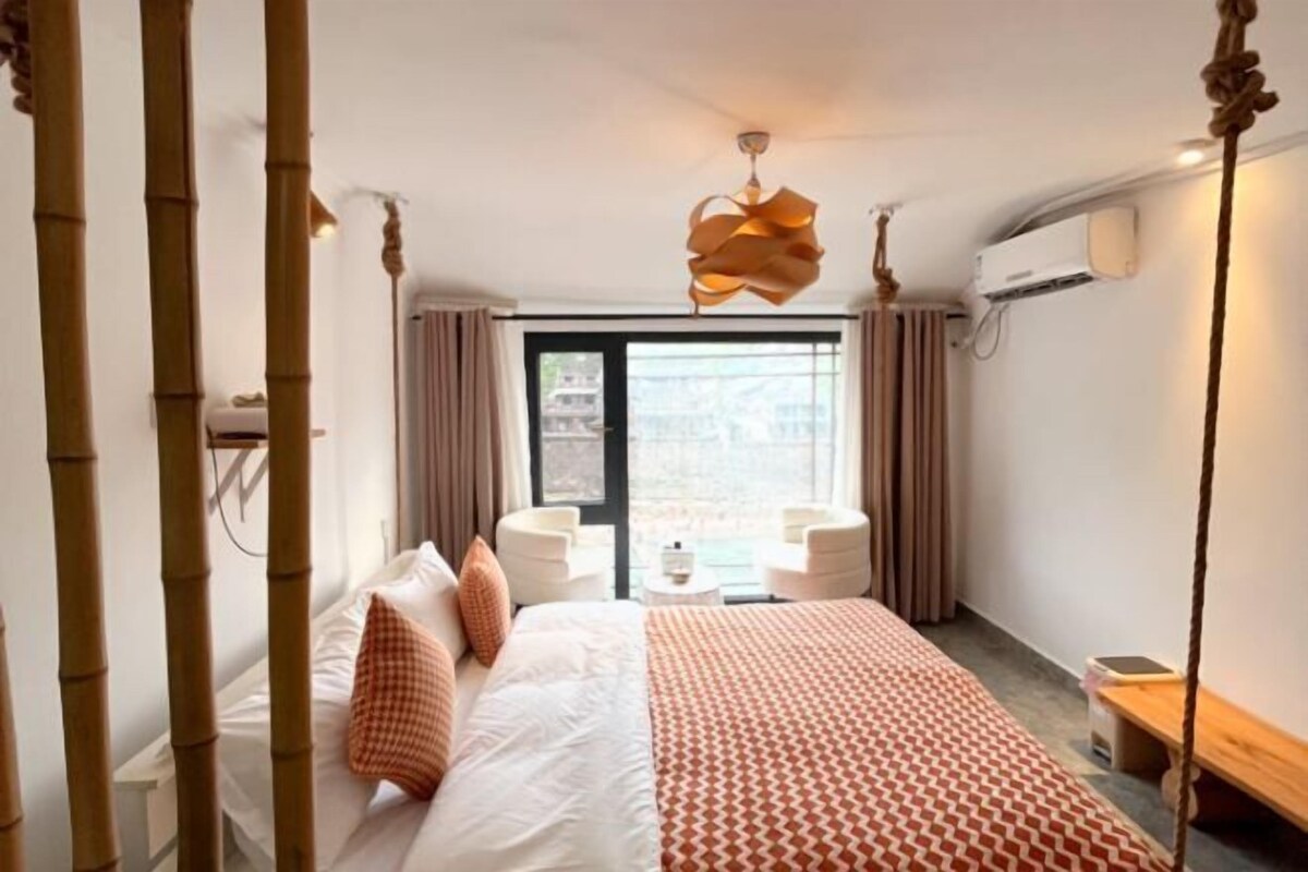 Habitación de hotel con una cama grande, un escritorio y una silla. Cuenta con una ventana con cortinas, una lámpara de techo y un aire acondicionado de pared.