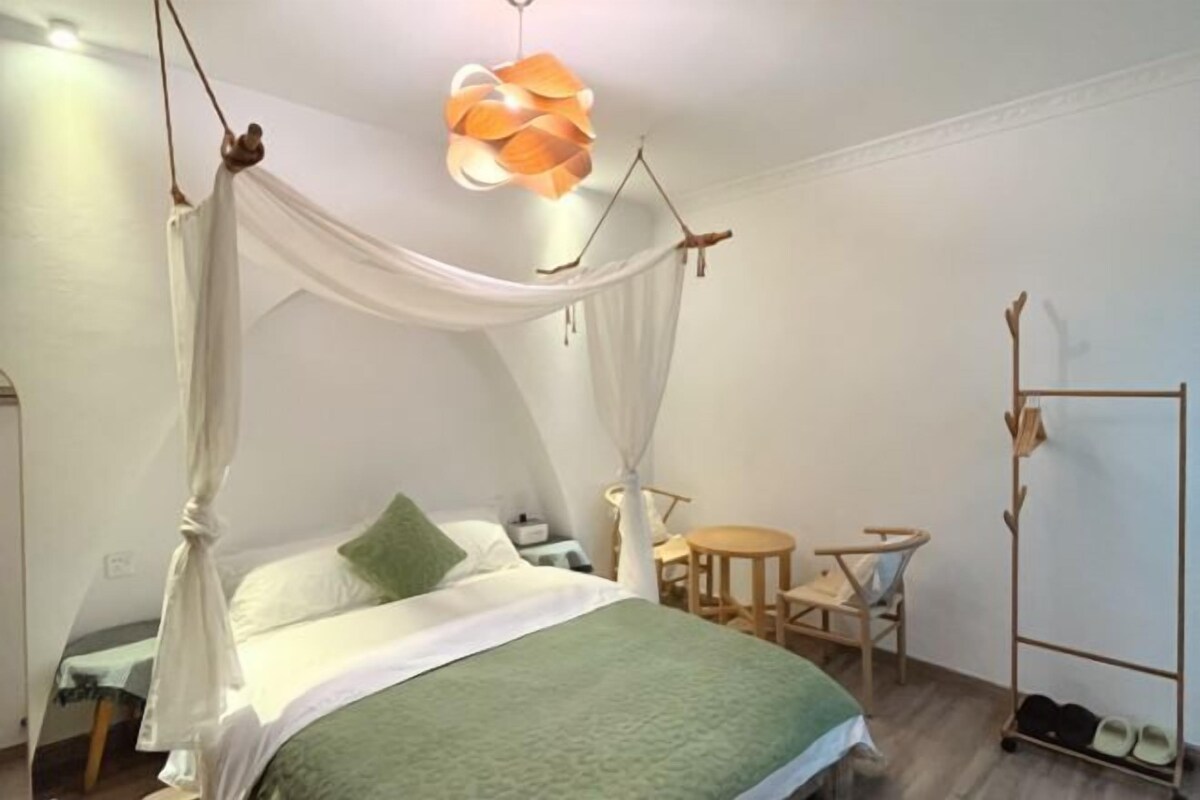 Un dormitorio con cama con dosel, una mesita redonda y un zapatero.