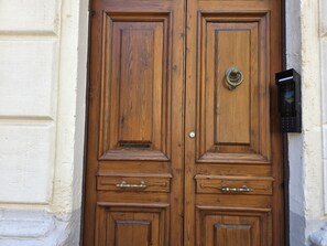A wooden double door with a keyhole and a doorbell.