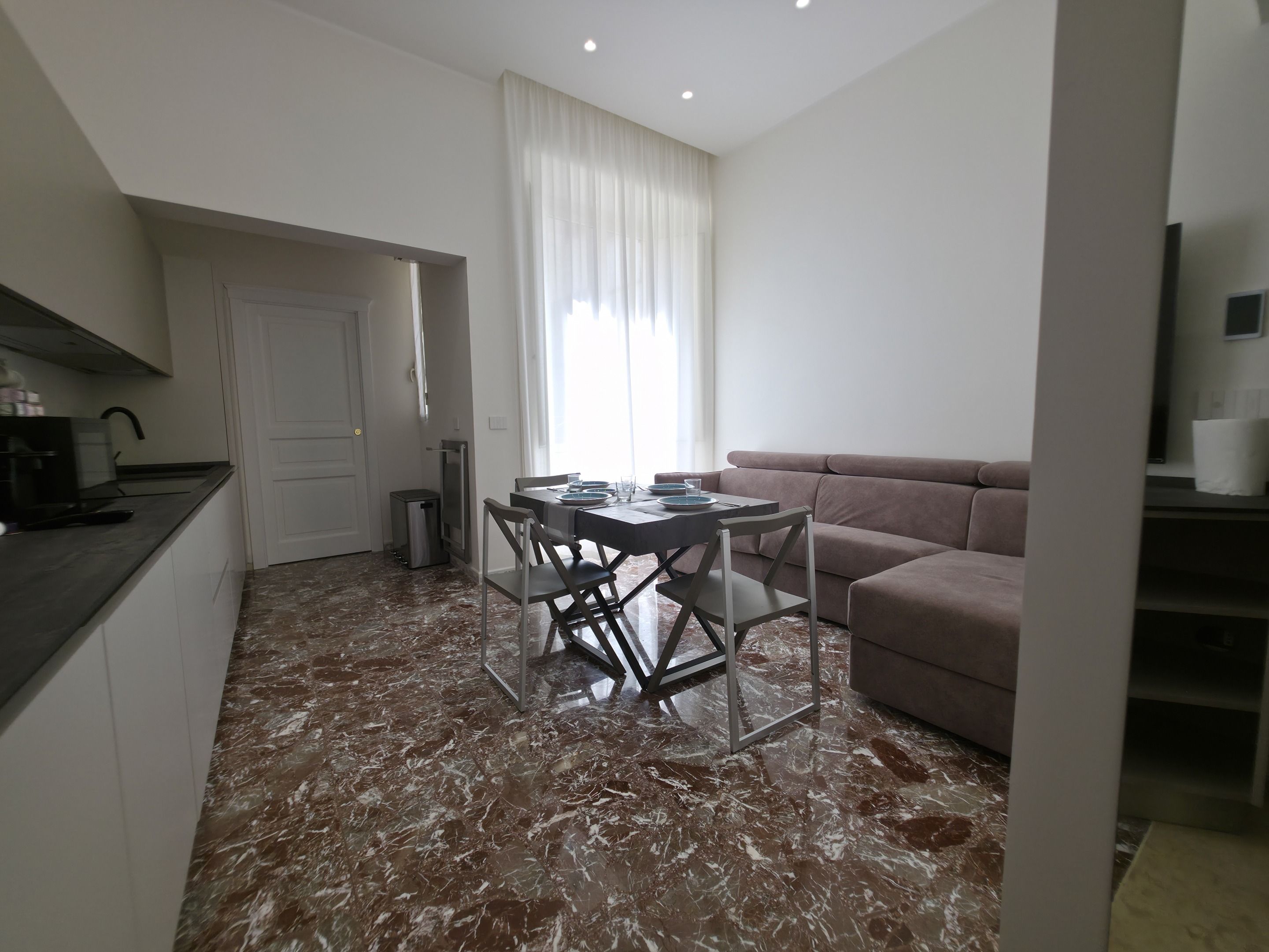 A compact living space with a dining table, chairs, a sofa, and a kitchenette.
