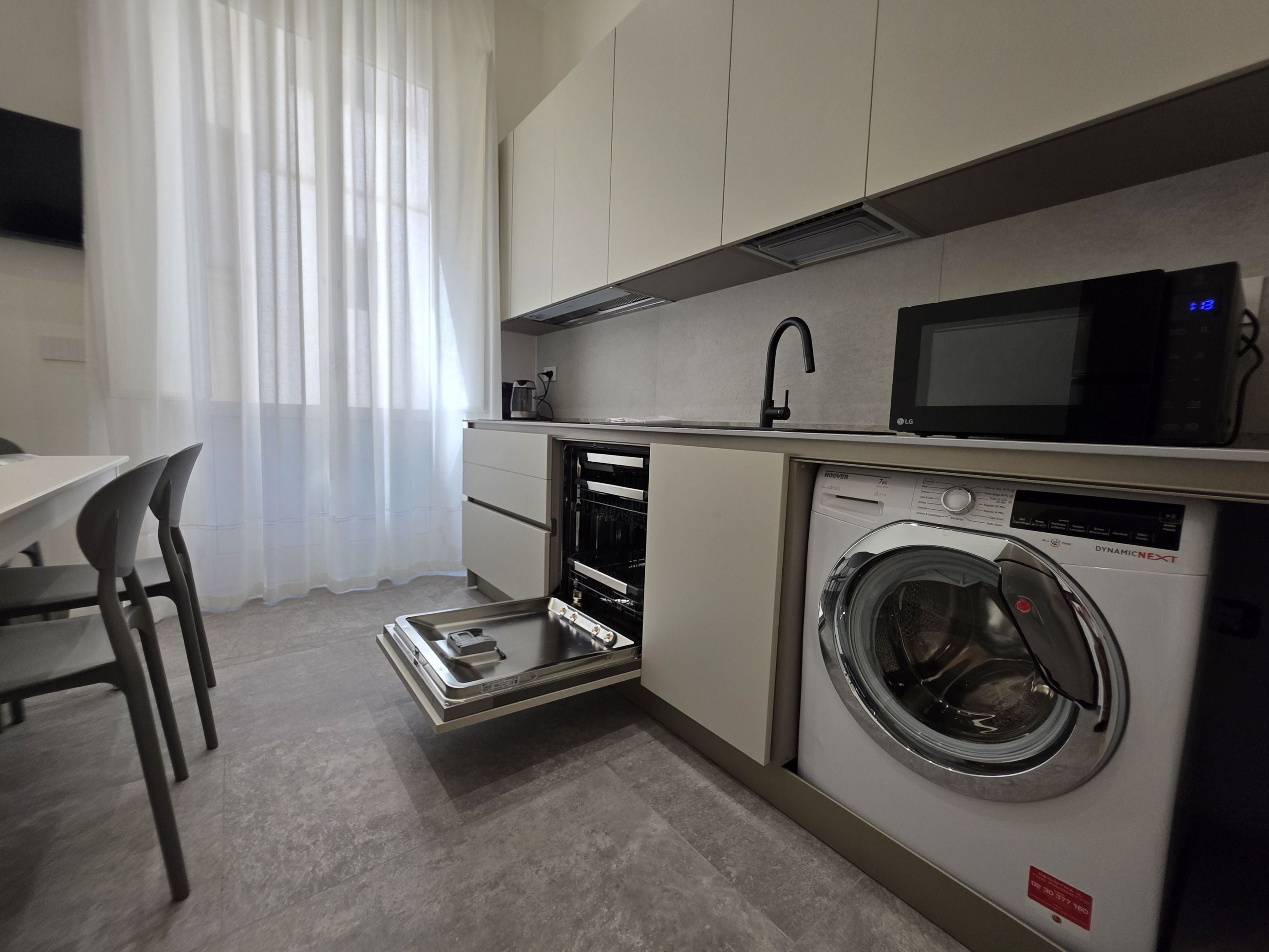 A compact kitchen with a built-in washing machine, a microwave, and a sink.
