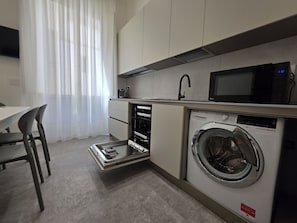 A compact kitchen with a built-in washing machine, a microwave, and a sink. - Domus Arconti (Reggio Calabria)